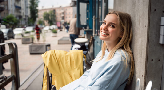 Ung kvinne på kafe i solskinn. Til artikkel om at visse grupper unge kvinner er mer tilfreds med livet