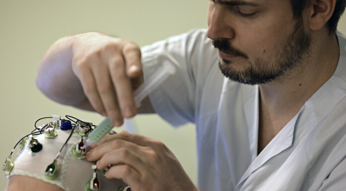 Migrene. Foto viser en mann som har på seg en hette med EEG-elektroder