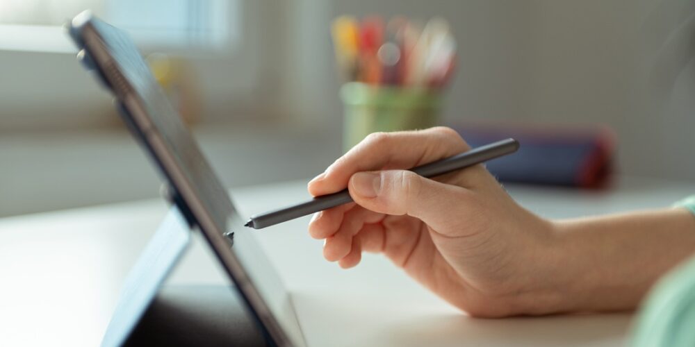 Bildet viser en hånd som skriver på et nettbrett.