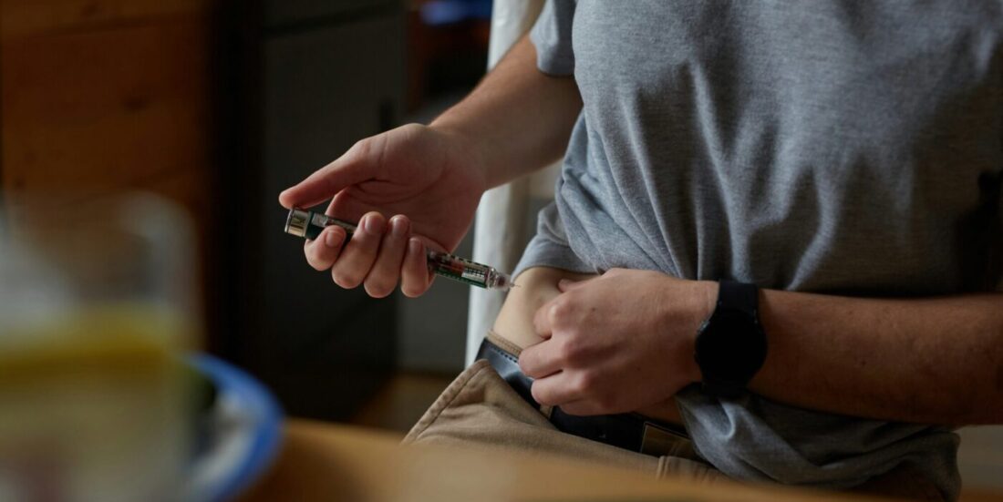 En mann setter en insulinsprøyte i magen.