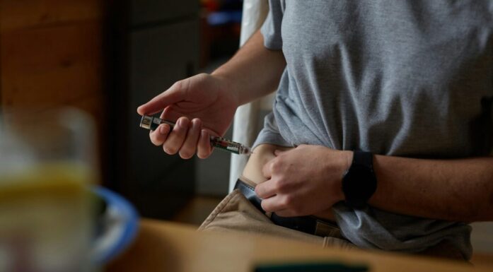 En mann setter en insulinsprøyte i magen.