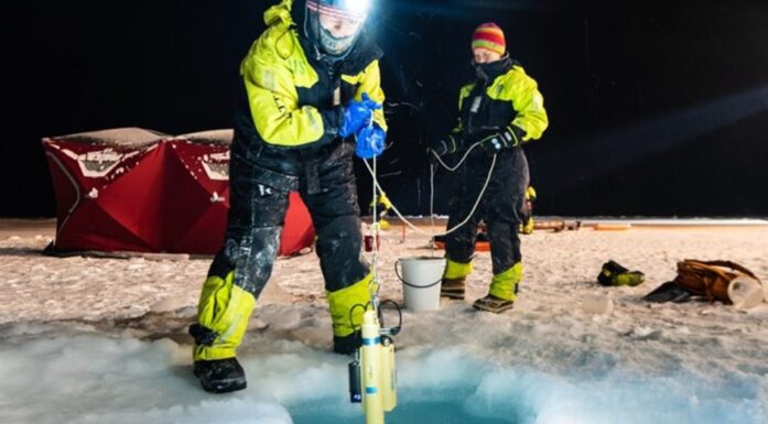 Arktis. Bildet viser to forskere ved et hull i isen.