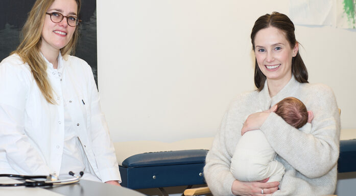 Foto av en kvinnelig lege og en mor med med baby på et legekontor.