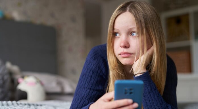 Nettmobbing. Bildet viser ei jente med mobiltelefon.