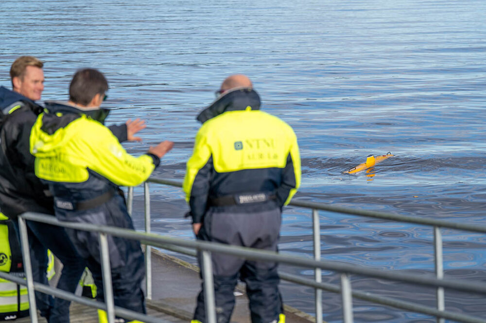 Ammunisjon: Tre menn ser på robot på vannet