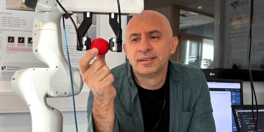 Forsker Ekrem Misimi i SINTEF viser fram roboten som kan "føle" som en menneskehånd. Her holder roboten et jordbær.
