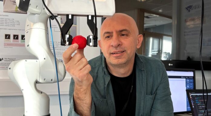 Forsker Ekrem Misimi i SINTEF viser fram roboten som kan "føle" som en menneskehånd. Her holder roboten et jordbær.