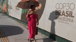 COP30. Bildet viser en kvinne som går forbi et banner med reklame for COP30.