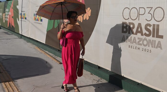 COP30. Bildet viser en kvinne som går forbi et banner med reklame for COP30.