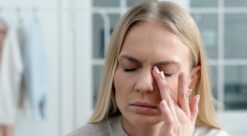 Hodepine. Bildet viser en kvinne som tilsynelatende har hodepine.