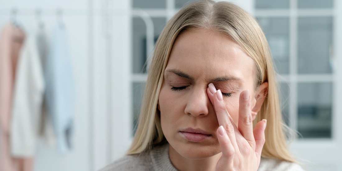 Hodepine. Bildet viser en kvinne som tilsynelatende har hodepine.