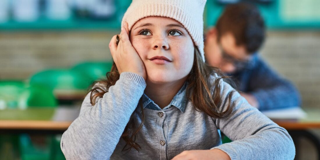 Jente som sitter ved skolepult og ser drømmende ut. Illustrasjon til artikkel om ADHD-forskning.