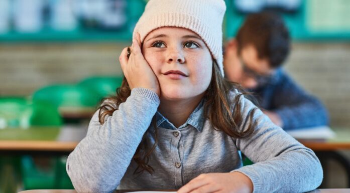 Jente som sitter ved skolepult og ser drømmende ut. Illustrasjon til artikkel om ADHD-forskning.
