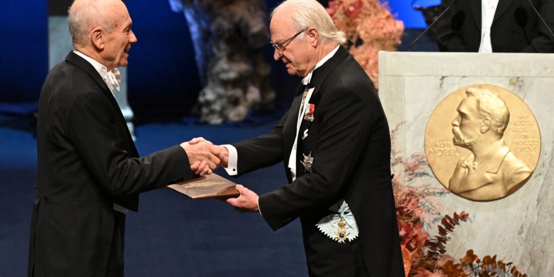 Mann i kjole og hvitt får diplom av Sveriges kong Carl Gustaf