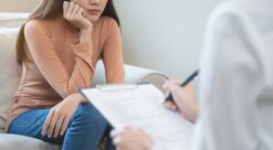 Bildet viser en kvinne på en sofa sammen med en terapeut som skriver.