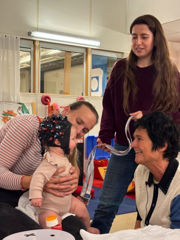 Bildet viser baby Live med hårnett og flere voksne rundt.