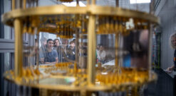 Gløtt inn i superdatamaskin, gullaktige komponenter i forgrunnen, studenter i bakgrunnen