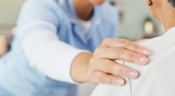 Sykepleier holder i skuldra til pasient.