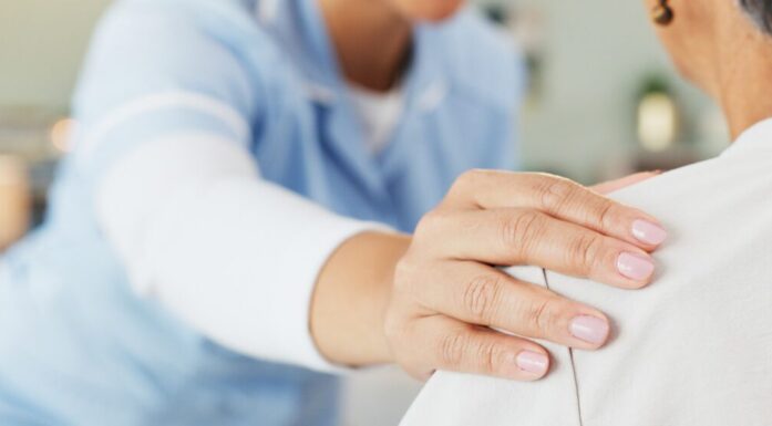 Sykepleier holder i skuldra til pasient.