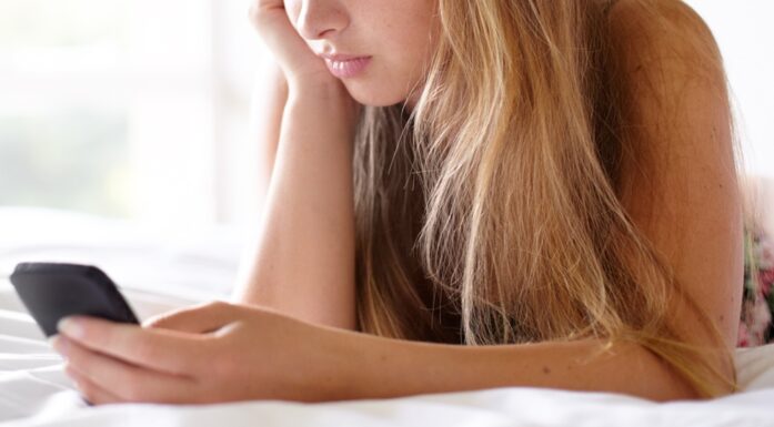 Sexting. Bildet viser en jente som ligger på sengen med en mobiltelefon.