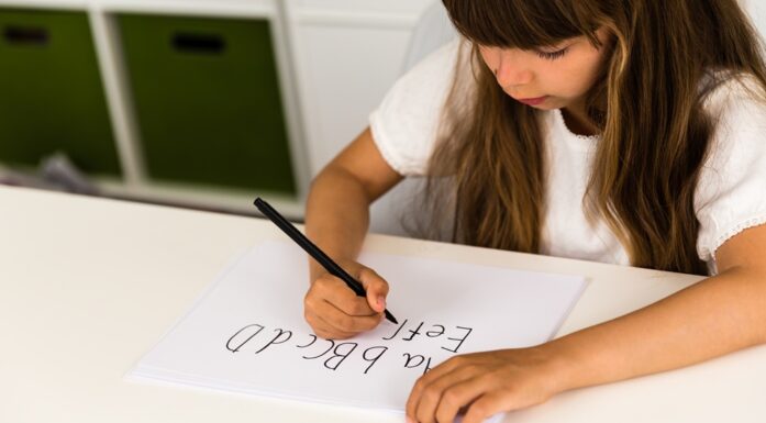 Øvelse. Bildet viser ei jente som skriver bokstaver for hånd.