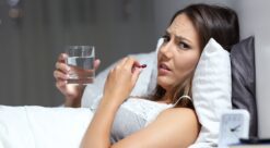 Bildet viser en kvinne som ligger i sengen mens hun tar en pille.