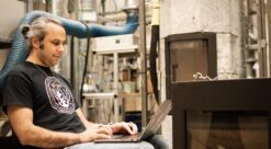 Vedfyring. Bildet viser Abolfazl Mohammadabadi med laptop foran en vedovn ved Varmeteknisk laboratorium ved NTNU.