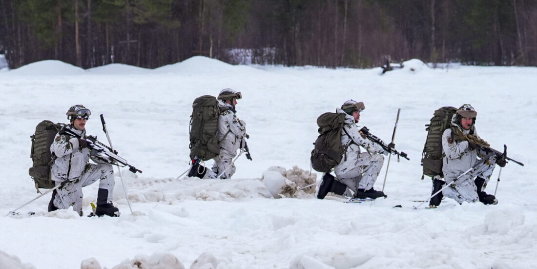 Firer soldater i vinterutrustning går i dyp snø.