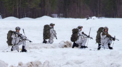 Firer soldater i vinterutrustning går i dyp snø.