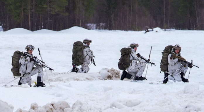 Firer soldater i vinterutrustning går i dyp snø.