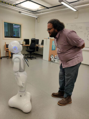 Bildet viser roboten Pepper og student Suraj De.