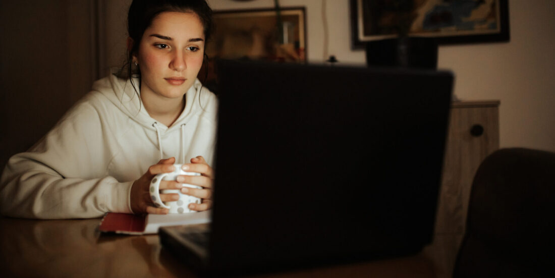 Ung jente sitter med en pc i mørket. Illustrasjonsfoto brukt til sak om mental helse og Chat GPT.