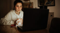 Ung jente sitter med en pc i mørket. Illustrasjonsfoto brukt til sak om mental helse og Chat GPT.