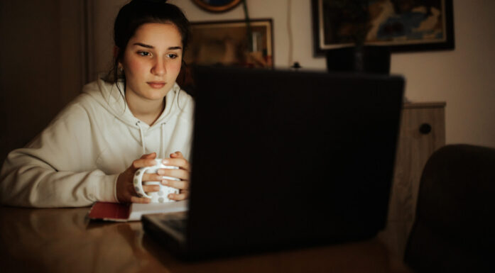 Ung jente sitter med en pc i mørket. Illustrasjonsfoto brukt til sak om mental helse og Chat GPT.