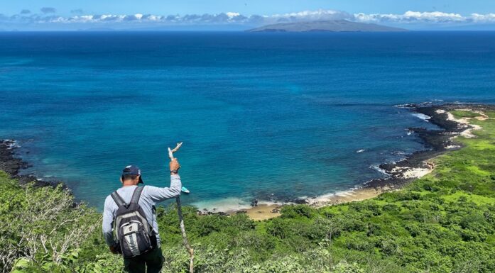 Evolusjon. En guide på Galapagos klatrer i fjellene med havet i bakgrunnen.