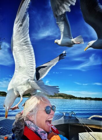 Leende kvinne med måke på hodet. Foto. 