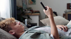 Demokrati. En ung mann i en sofa som ser på mobiltelefonen.