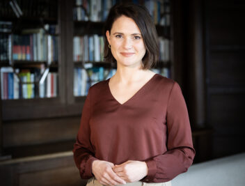 Kvinne foran en bokhylle. Foto 