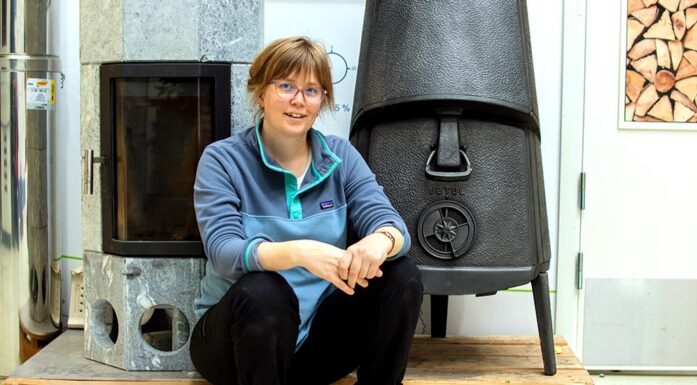 Sofie Sødal Eiksund sitter foran to typer vedovner. Foto.