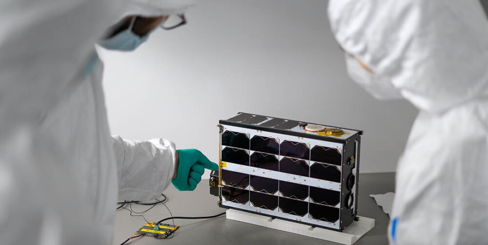 Forskere ser på en liten satellitt på bordet