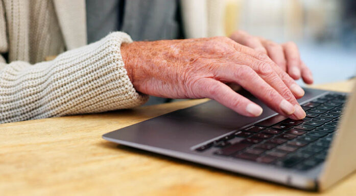 Eldre persons hender på tastatur. Foto.