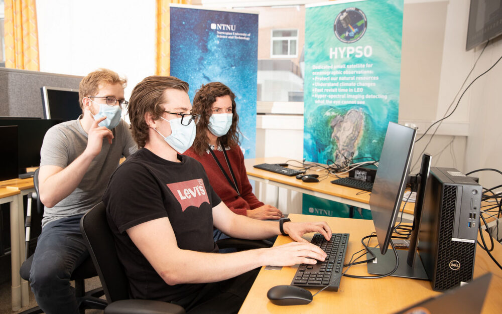 Tre forskere sitter foran en datamaskin. Foto.