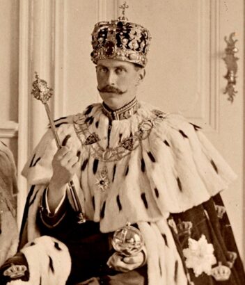 En mann krone på hodet og hermelinskappe på skuldrene. Historisk foto. 