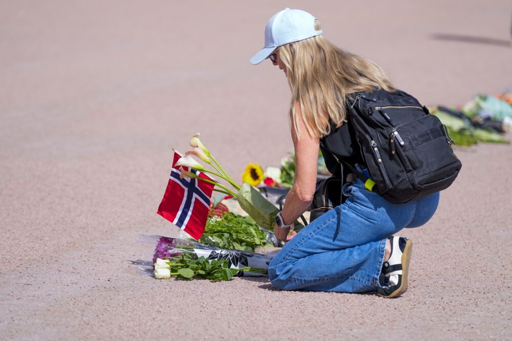 En kvinne legger blomster foran slottet.